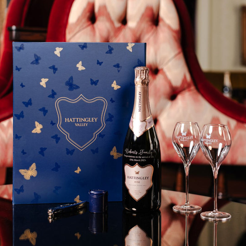 Lifestyle image of Hattingley Valley Luxury Gift Set with a bottle, two glasses and a stopper  
