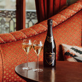 Lifestyle image of Hattingley Valley Kings Cuvée, premium sparkling english wine, image of filled flutes on table with Kings bottle beside, luxurious hotel interior in the background