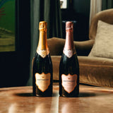 The festive duo, two bottles of Hattingley Valley English Sparkling sitting in a coffee table with a rich velvet chair in the background, the wines are Classic Reserve NV with a gold label and English Sparkling Rosé, with a pink label perfect for toasting the festive season