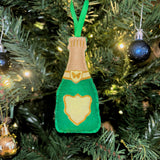 Green and gold champagne bottle ornament on a Christmas tree