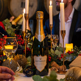 Bottle of Classic Reserve Hattingley Valley English Sparkling on a festive table with candles, holly and presents. Experience a wine tasting at Hattingley Valley Wines, winery in Hampshire vineyard near me