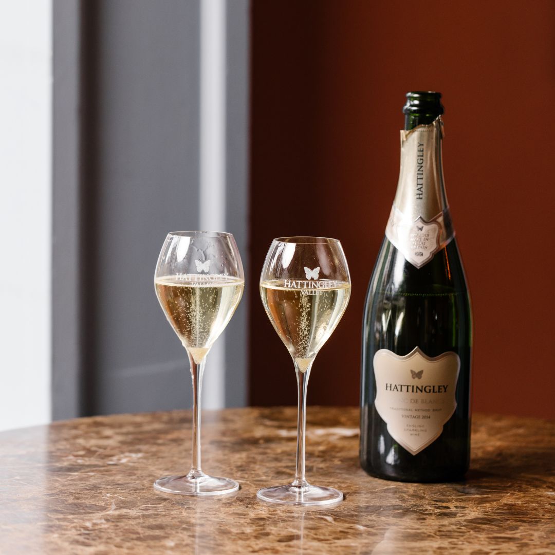 Image of our Hattingley Valley Blanc de Blancs on a table at home house members club London, two filled glasses of Hattingley Valley English sparkling beside 