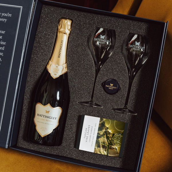 Hattingley Valley lifestyle image, Luxury gift set with candle, Classic Reserve bottle with Hattingley flutes, glass champagne flutes and Glass & Wick candle, champagne bottle stopper