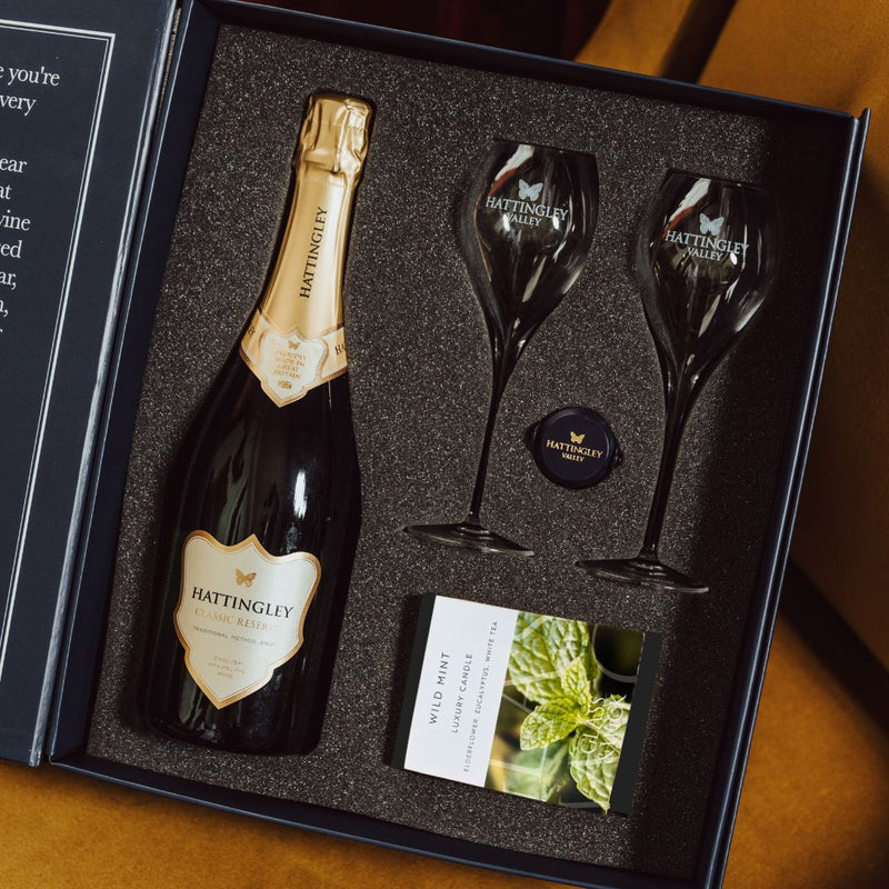 Hattingley Valley lifestyle image, Luxury gift set with candle, Classic Reserve bottle with Hattingley flutes, glass champagne flutes and Glass & Wick candle, champagne bottle stopper