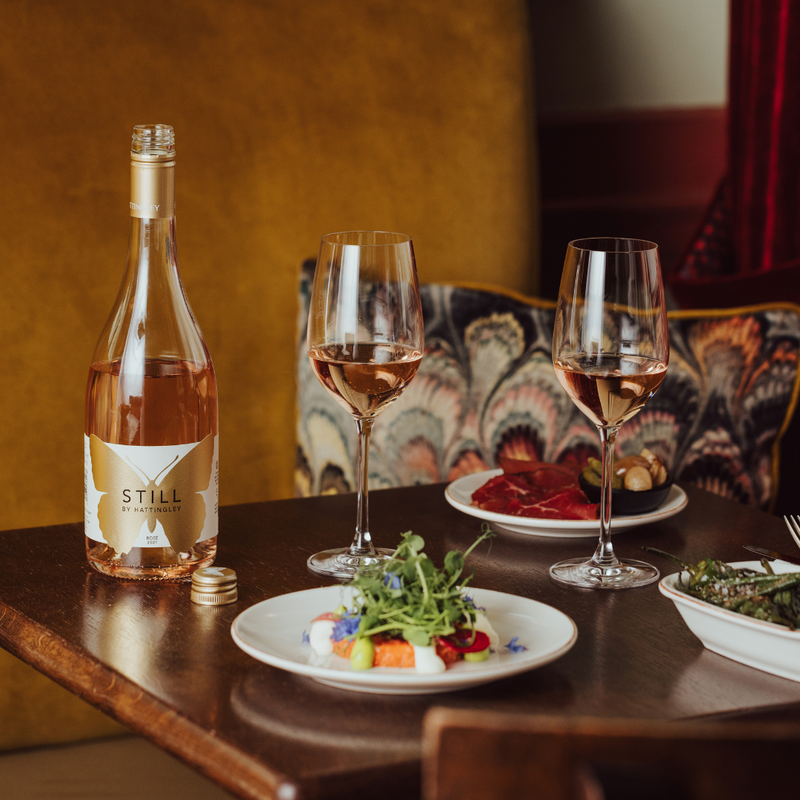 Still Rosé Lifestyle Image wine in glasses on a table of food, luxurious hotel background, Hattingley Valley English Rosé, Best English Rosé wines