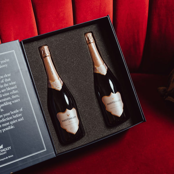 Hattingley Valley Birthday Luxury Gift Set, Lifestyle image, two sparkling Rosé bottles in a gift box with a luxurious hotel background, velvet sofa