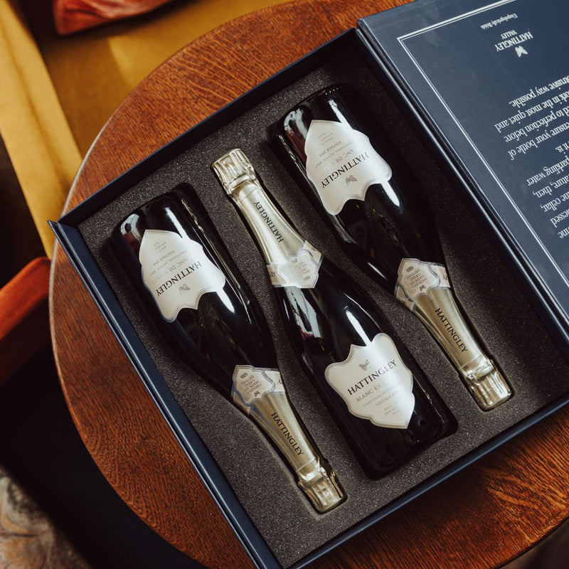 Hattingley Valley Congratulations Luxury Gift Set, three bottles of Blanc de blancs in a gift box on a table, with a luxurious hotel background