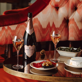 Hattingley Valley sparkling rosé, open bottle of rosé on table with filled glasses and delicious food pairings, luxurious hotel background.