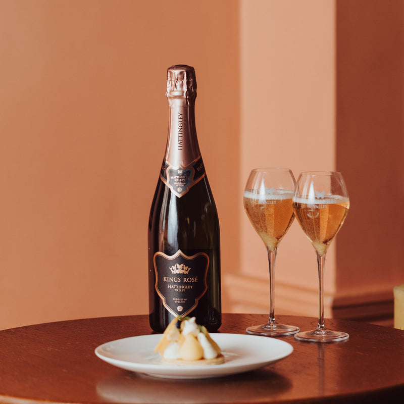 A lifestyle image showing a bottle of Hattingley Valley Kings Cuvée Rosé with a luxurious dessert