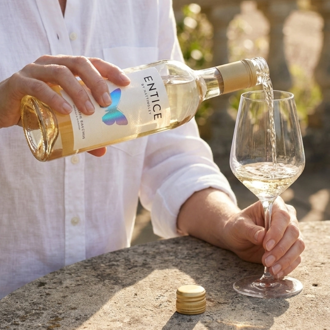 Bottle of Entice English Desert Wine with Silver butterfly label being poured on a sunny day in to a glass 