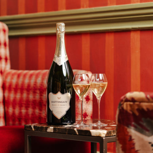 Hattingley Valley Blanc de Blancs Magnum with two filled glasses, Magnum bottle on table with luxurious hotel background