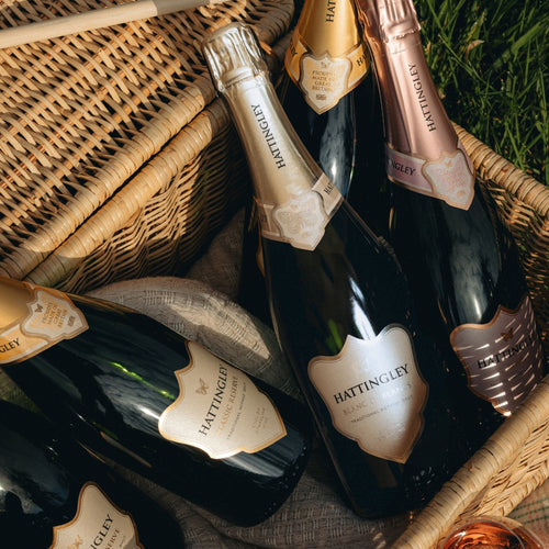 Hattingley English sparkling wine bottles in a picnic basket on grass