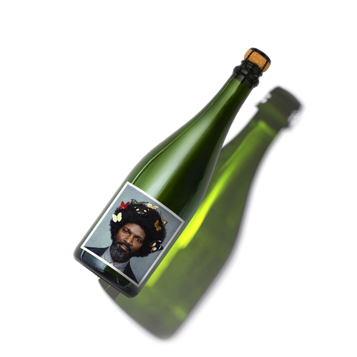 Bottle of The English Gent with a label featuring a man's face on a blue background with butterflies in his hair. Blend of Bacchus and Pinot Gris, traditional method English Sparkling.