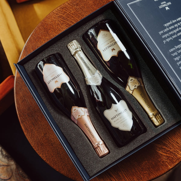A Hattingley Valley Luxury Gift Set open on a small table, on show are three bottles of English Sparkling Wine: Hattingley Valley Classic Reserve, Sparkling Rosé and Blanc de Blancs