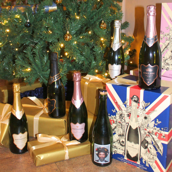 Bottles of champagne and presents under a decorated Christmas tree.