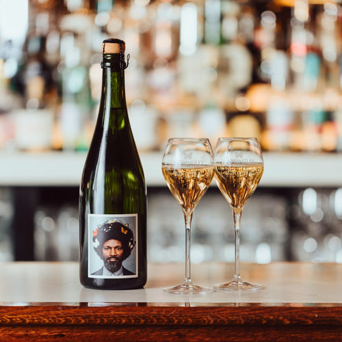 A bottle of English gent English Traditional Method Sparkling Wine on a bar with two poured glasses behind