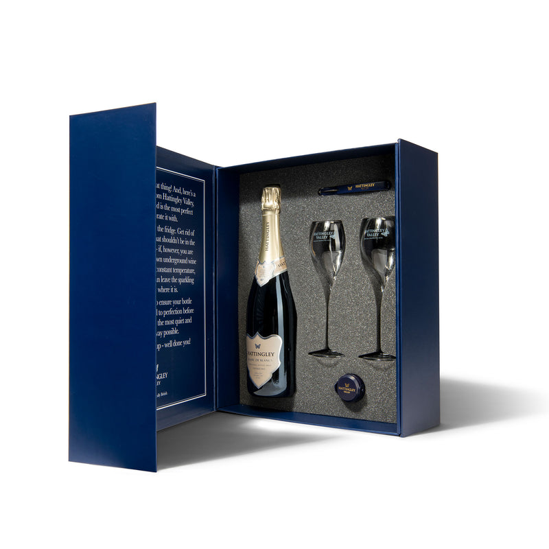 Hattingley Valley luxury gift box set. Gift box open displaying inside, with one bottle of Hattingley Valley English Sparkling Blanc de Blancs, two tulip flutes with the Hattingley logo on them and a Hattingley bottle stopper and waiters friend.